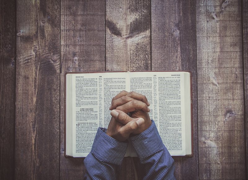 Praying hands above a bible